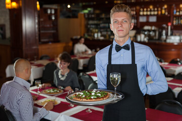 Handsome elegant waiter with serving tray welcoming to restaurant..