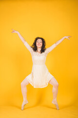 Fototapeta na wymiar Graceful classic ballerina dancing on yellow studio