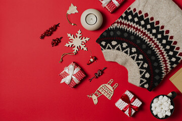 Fashion flat lay knolling with cozy sweater and gift box on red background