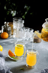 Homemade citrus tea in stylish glassware side view