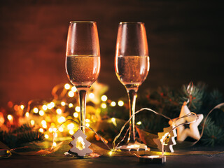 Romantic Christmas, two glasses of champagne on a dark festive table with a yellow garland.