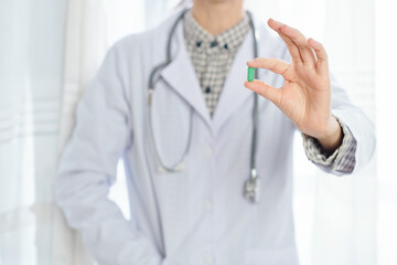 Close-up image of general practitioner showing green vitamin pill