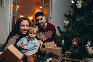 family with on kid decorating christmas tree and packing presents at home