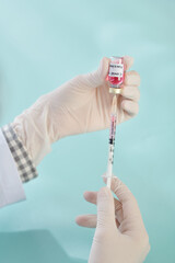 Hands of general practitioner holding syringe and vial with vaccine against coronavirus