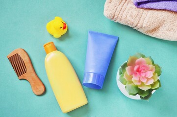 Wooden comb, natural shampoo, face cream, towels and decorative plant. View from above beauty photography