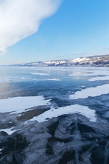 Beautiful landscape of frozen lake Baikal with blue transparent ice and snow-capped mountains on a Sunny frosty day in February. Winter holidays, ice travel. Natural background