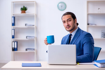 Young male employee drinking coffee during break