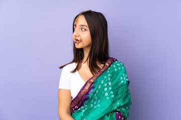 Young Indian woman isolated on purple background looking to the side