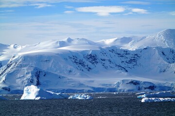 The foreground is a deep blue sea. The iceberg is in the middle of the scene. Blue sky and white clouds are the best background.
