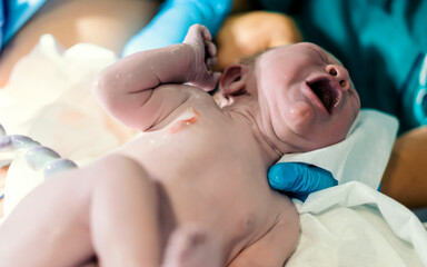 Crying newborn baby boy still with umbilical cord.