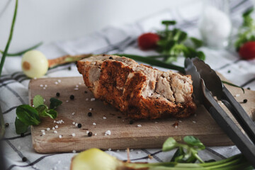 
The prepared indica breast lies on a tree board. Vegetables and peppers and salt are lying around.