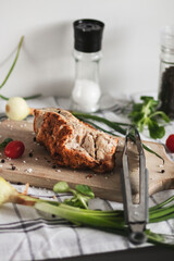
The prepared indica breast lies on a tree board. Vegetables and peppers and salt are lying around.