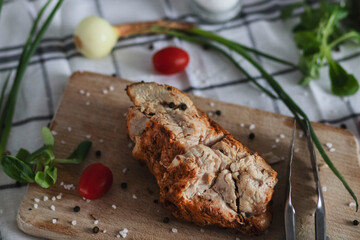 
The prepared indica breast lies on a tree board. Vegetables and peppers and salt are lying around.
