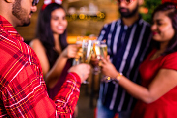 group of four indian friends cheering with champagne flutes and looking happy while having party on the kitchen at stay home quarantine corona virus outbreak party