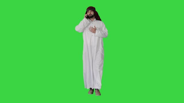 Arab sheikh making a call walking on a Green Screen, Chroma Key.