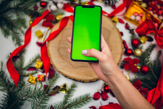 Top view of phone in female hand on festive  background. Christmas decorations. New Year time holiday. Mockup. 