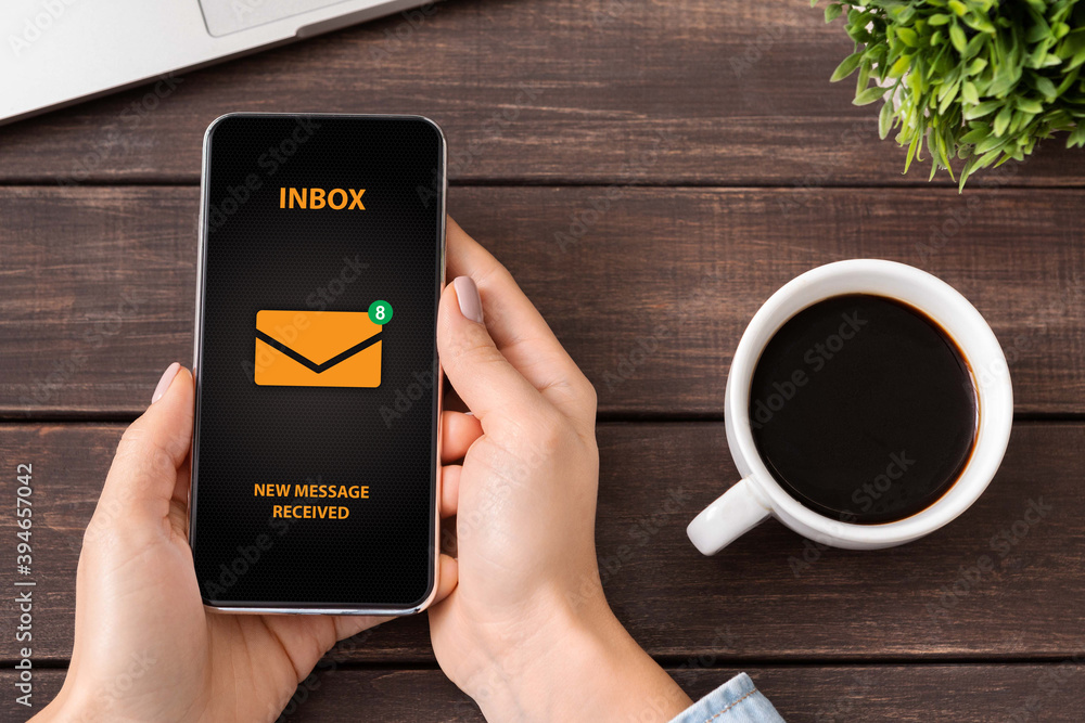 Poster young lady having new email messages in her inbox on smartphone at table, top view