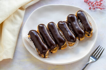 Chocolate eclairs on plate on white background