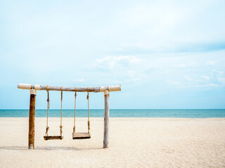 Empty brown twin wooden swings on the beach.