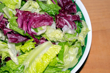 close-up of a fresh  salad with iceberg lettuce and radicchio, in a bowl ,on wooden background. selective focus