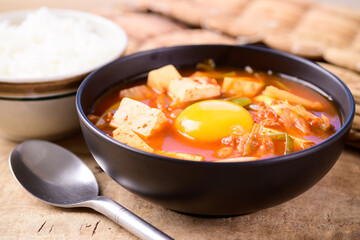 Korean food, Kimchi soup with tofu and egg eating with cooked rice on wooden background