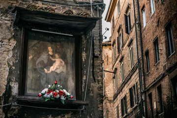 Mit Blumen dekoriertes Heiligenbild in Siena, Italien
