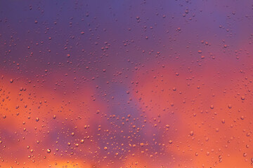 Rain water drops pattern on a window glass surface at a pink sunset