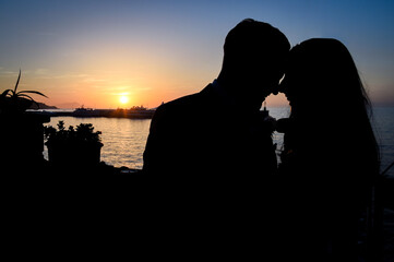 Silhouette di una coppia innamorata che si bacia al tramonto in riva al mare