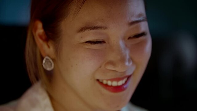 Young Asian Woman Laughing While Working Late in Office
