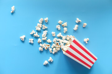  popcorn spilling from a container on blue background 