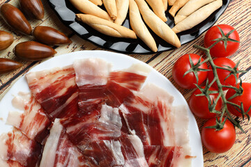 Portion of acorn-fed Iberian ham and bread spikes garnished with acorns and cherry tomatoes
