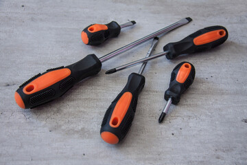 Construction and repair tools. Set on a wooden background. Metal screwdrivers and pliers with black and orange handles. Equipment for electrician, plumber and installer