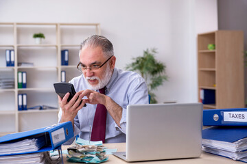 Old male accountant in budget planning concept in the office