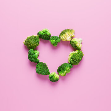 Heart shape made from fresh raw broccoli on pink background