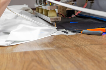 Men's hands work at the machine for welding PVC film and edging seam. Shop for the production of stretch ceilings.