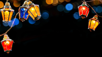 Glowing Xmas lights in black night. colorful Ffairy christmas lights with vintage lantern shaped lamps .
