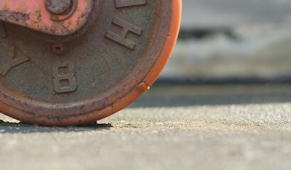Close-up a front veiw of a vintage orange rubble roller on the cement grounds of a forklift wheel.