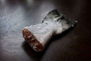 frozen salmon tail on a dark kitchen table