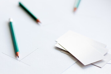 white business cards on a white sheet of paper, two pencils side by side and the beginning of the diagram drawn in pencil