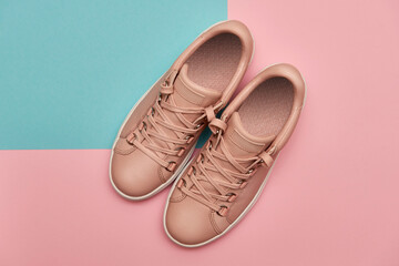 Stylish pink female shoes on pastel background, copy space. New sneakers on pink and blue background. Beauty and fashion concept. Flat lay, top view. Overhead shot