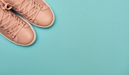 Stylish pink female shoes on pastel background, copy space. New sneakers on pink and blue background. Beauty and fashion concept. Flat lay, top view. Overhead shot