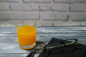 Still life with notepad, glass of juice and pen on the wooden background