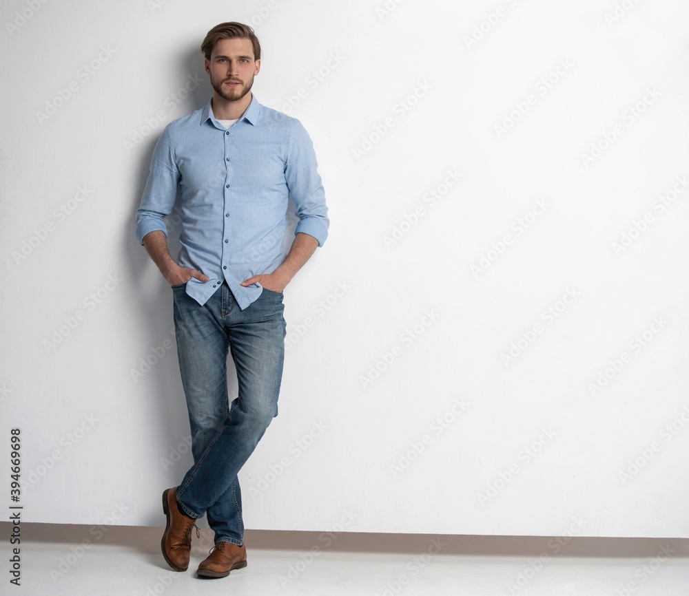 Wall mural Full length studio portrait of casual young man in jeans and shirt. Isolated on white background.