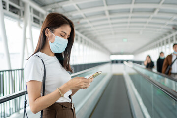 Portrait of a young woman in a medical mask for anti-coronavirus COVID-19 pandemic infectious disease outbreak protection and use a smartphone in Public area. Concept of Virus pandemic and pollution