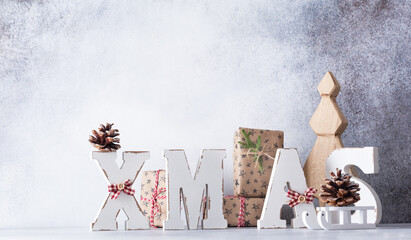 Wooden letters XMAS and decorative Christmas tree, star, cone, gifts box on light gray background. Zero waste Christmas concept.