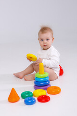 baby girl playing with colorful rainbow toy pyramid sitting on floor