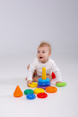 baby girl playing with colorful rainbow toy pyramid sitting on floor