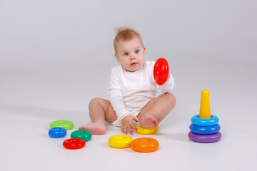 baby girl playing with colorful rainbow toy pyramid sitting on floor