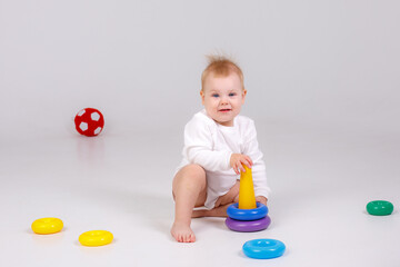 baby girl playing with colorful rainbow toy pyramid sitting on floor