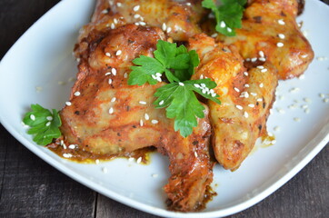 Spicy hot chicken wings cooked with honey and soy, topped with sesame seeds, served with sauce, celery and carrot sticks
